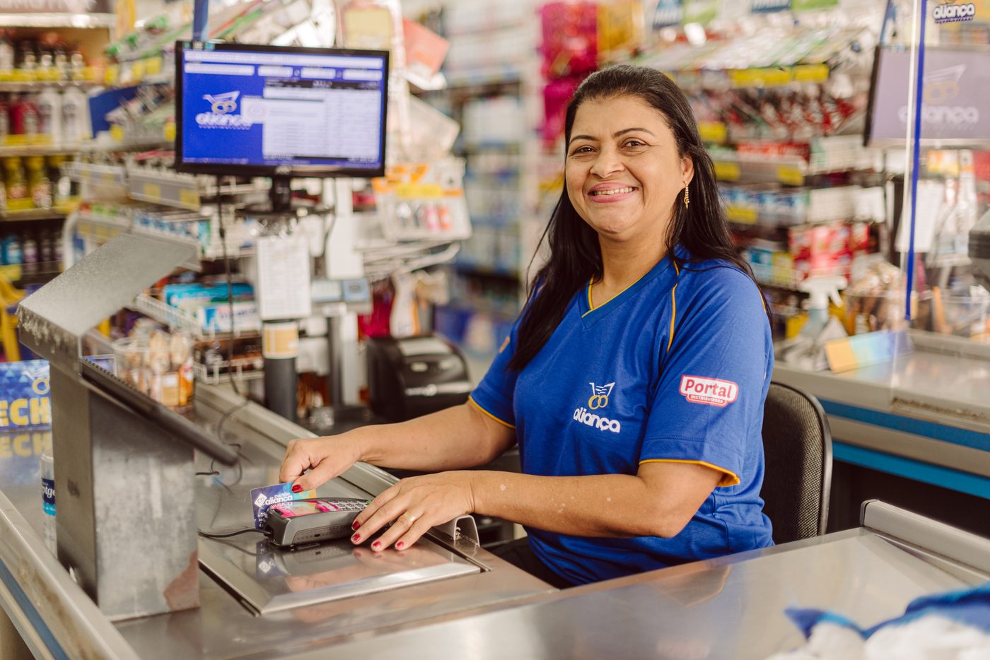 Operadora de caixa do Supermercado Aliança sorrindo durante o atendimento