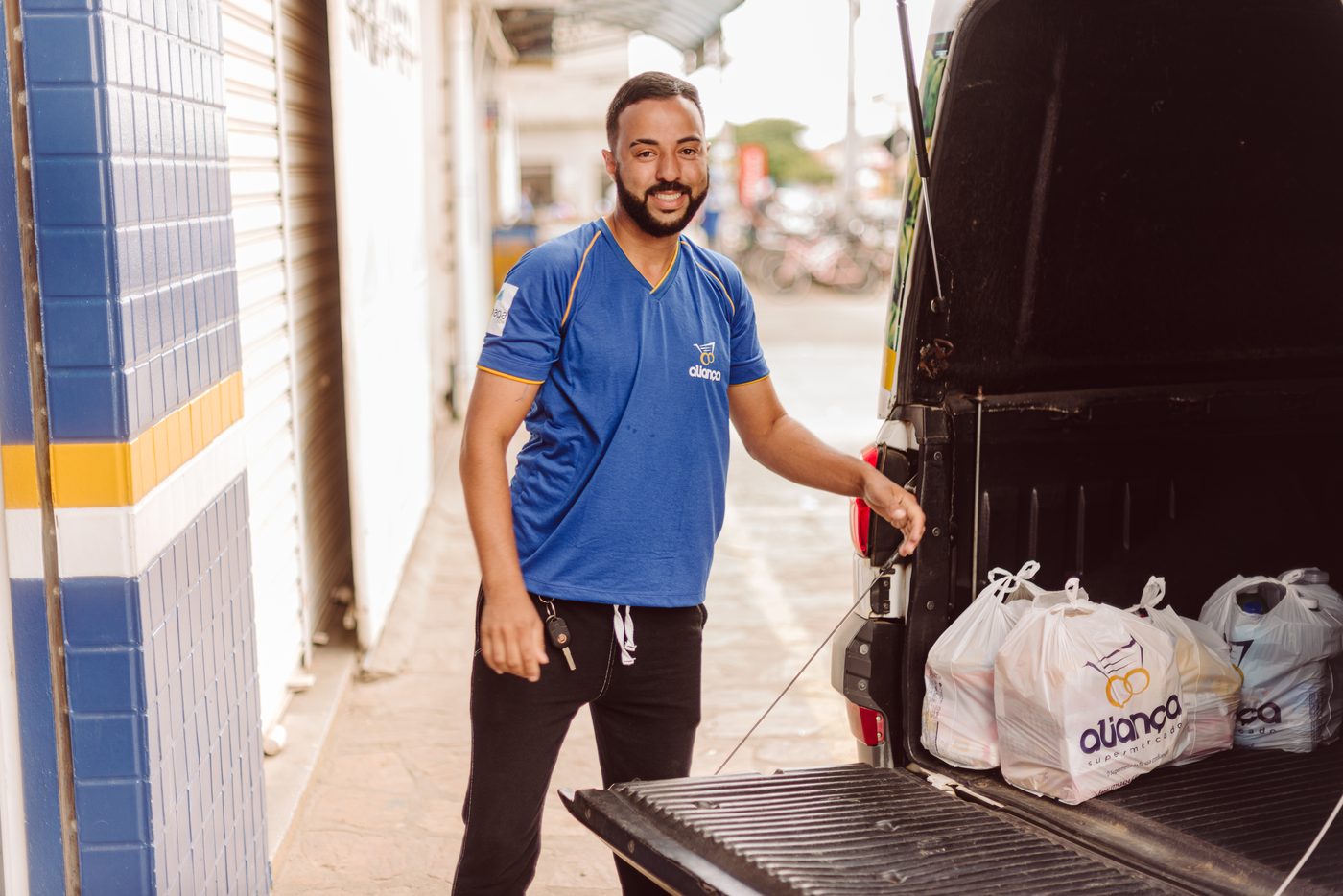 Colaborador do Supermercado Aliança carregando o veículo de entregas com as compras dos clientes
